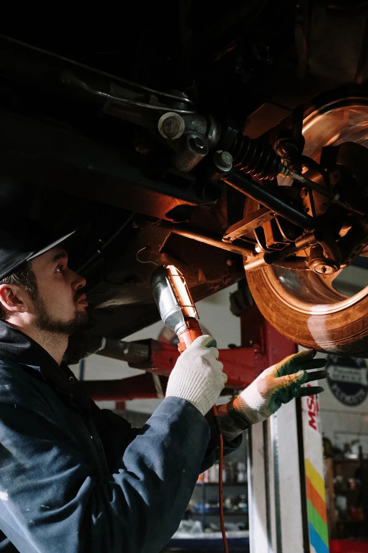 Mecánico trabajando en la parte inferior de un automóvil elevado